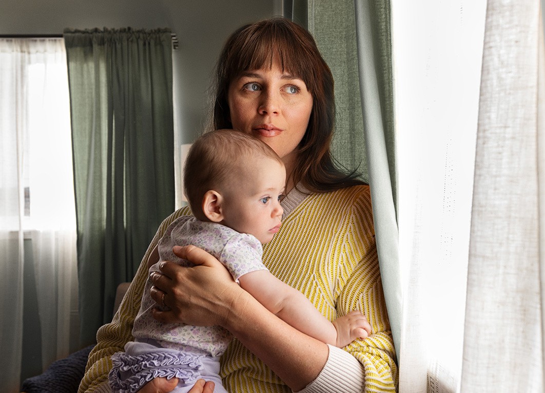 Woman holding baby looking out the window