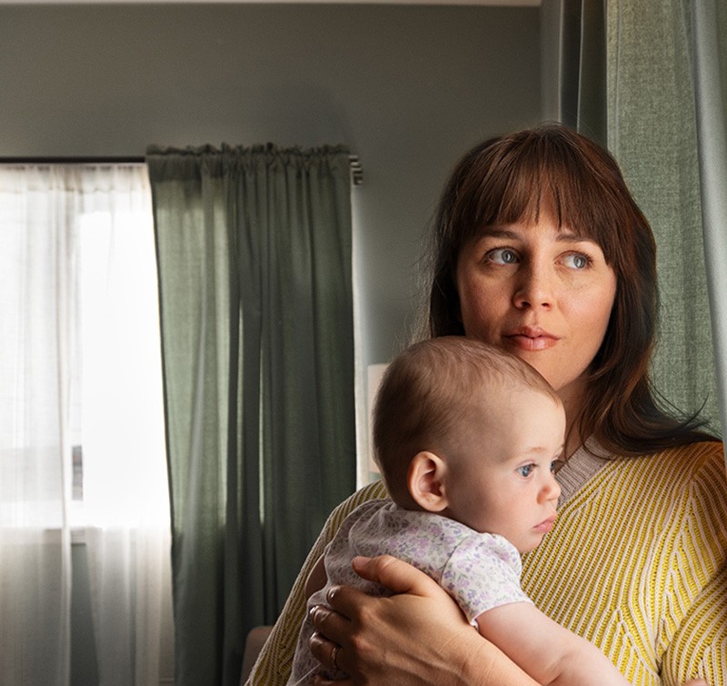 Woman holding baby looking out the window