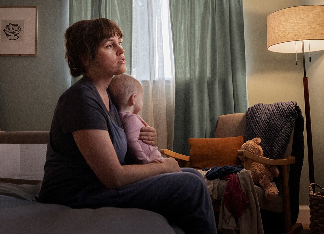 Woman in a green shirt holding her baby in bed