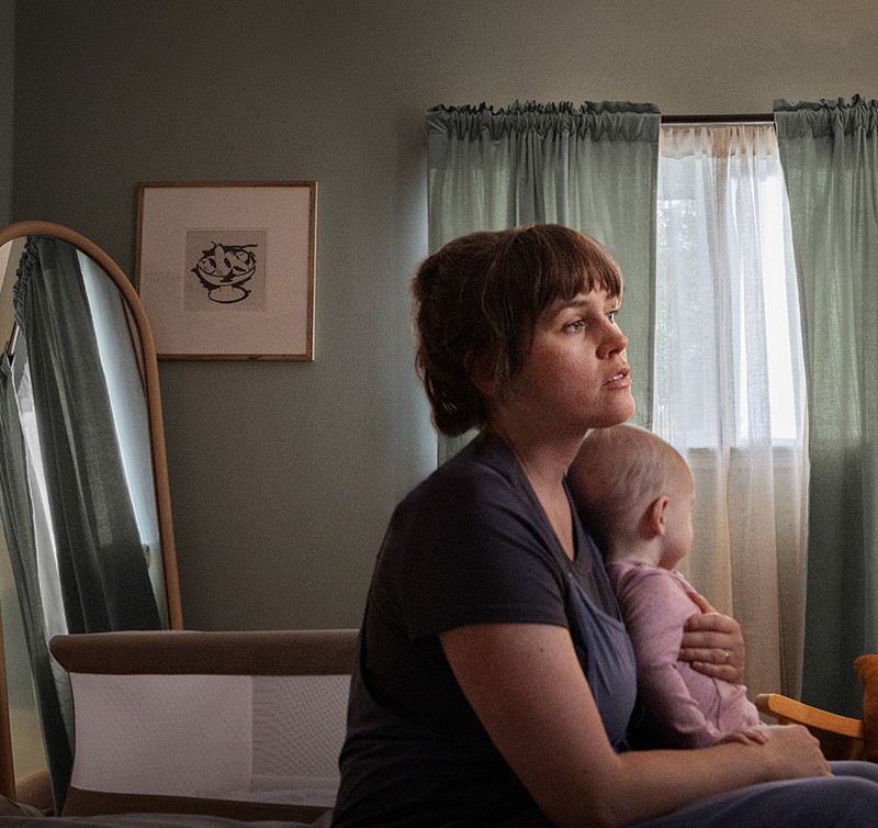 Woman in a green shirt holding her baby in bed